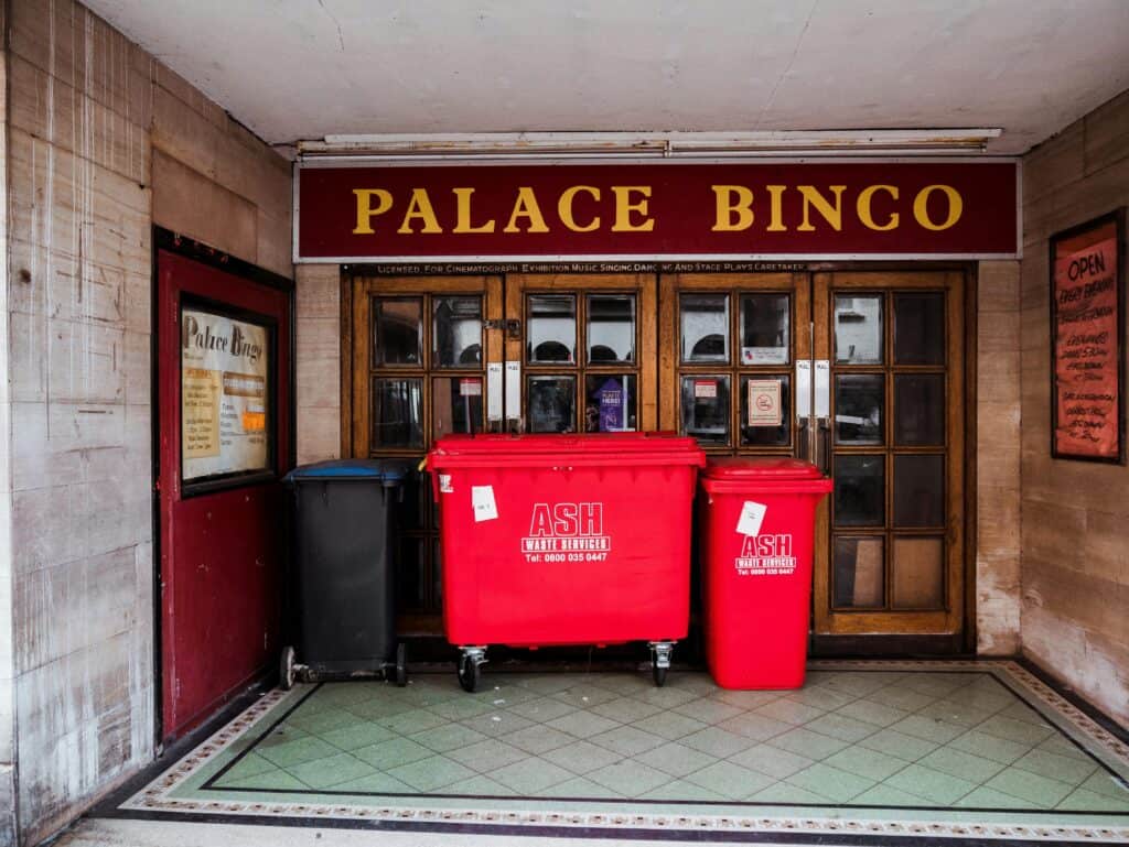 Front view of Palace Bingo entrance in Conwy with red waste bins outside. Urban street scene.